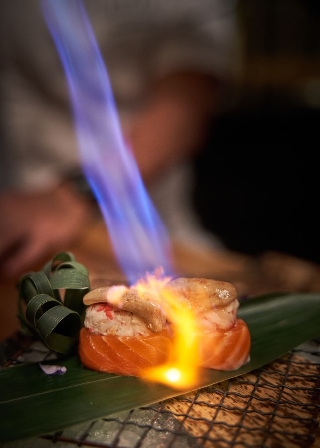Salmón flameado con soplete sobre una hoja